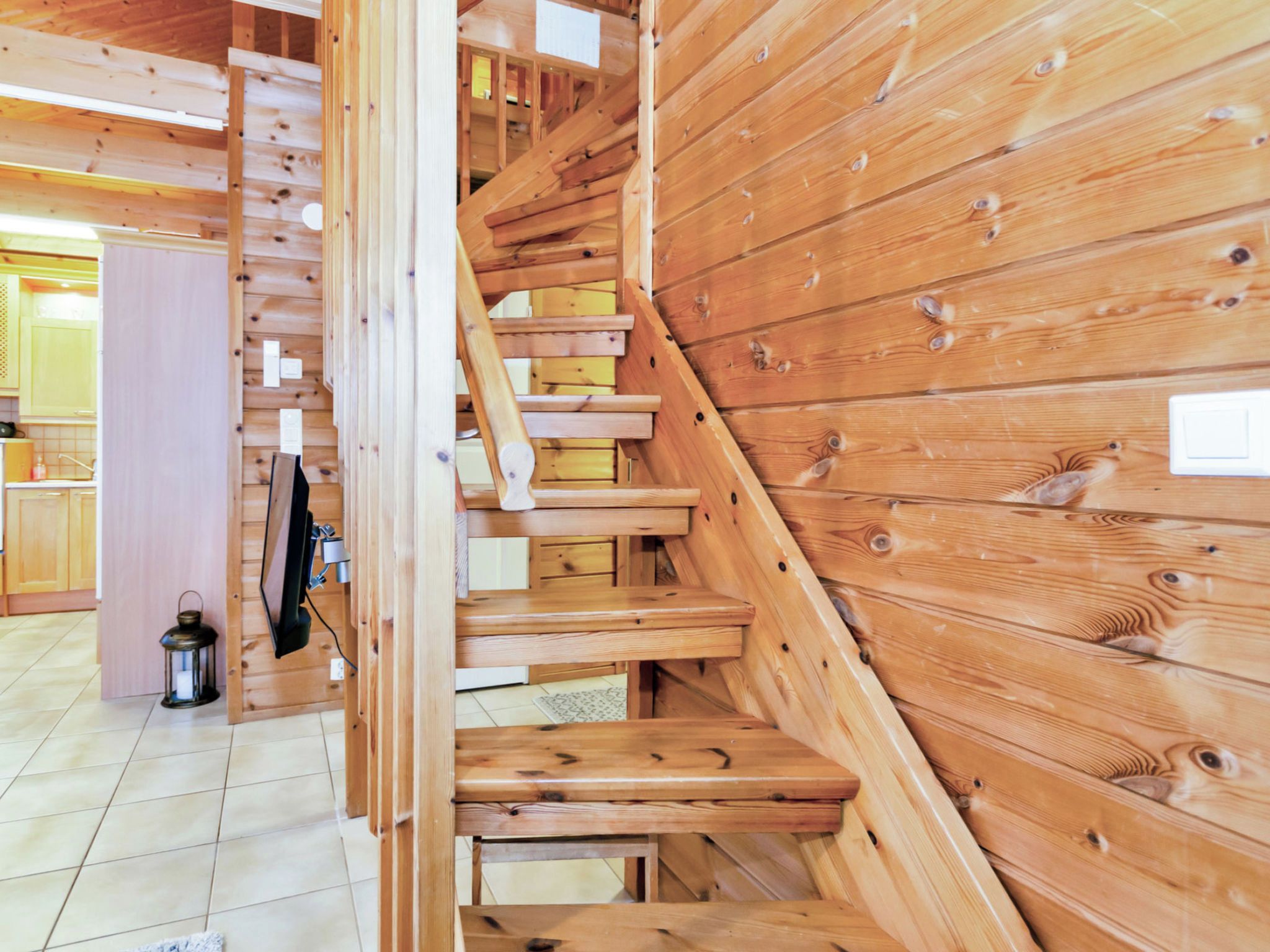 Eine Holztreppe in einem rustikalen Interieur, im Hintergrund ist eine Küche erkennbar.