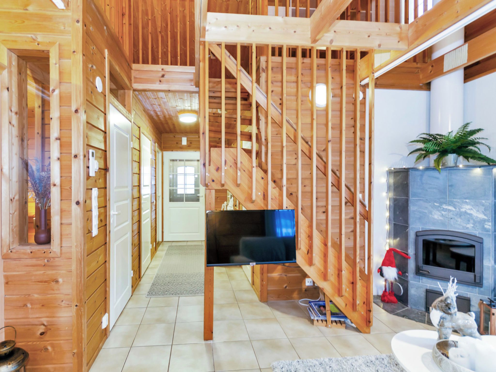 Un interior de madera con una escalera, una chimenea y un televisor.