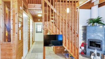 Un interior de madera con una escalera, una chimenea y un televisor.