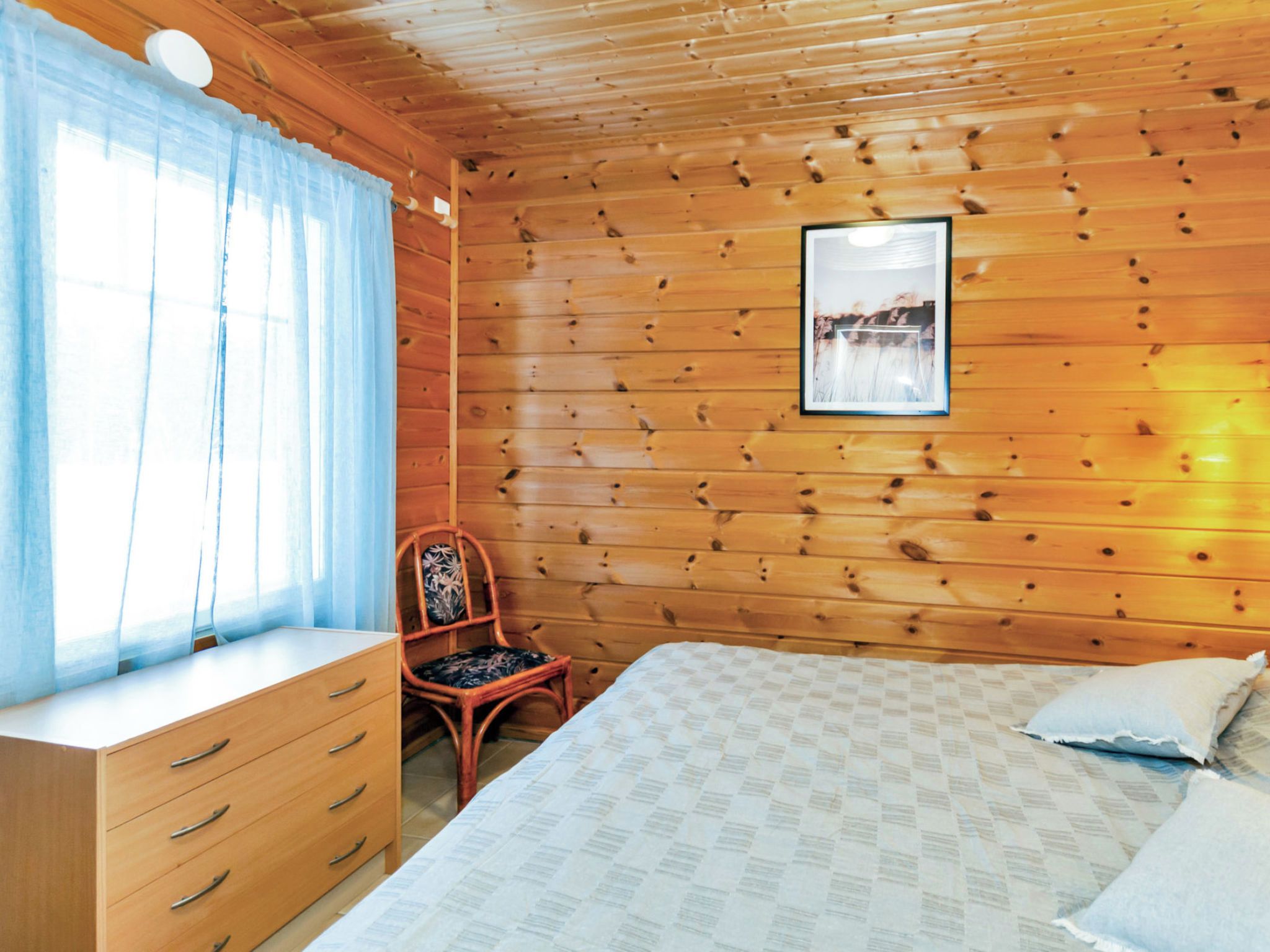 Une pièce de style cabane en bois, avec un lit, une chaise, une commode et un tableau encadré au mur.