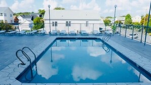 A rectangular swimming pool with a clear blue water surface, surrounded by a tiled deck and metal railings.