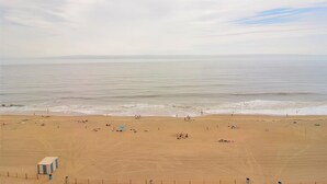 A wide sandy beach with a lifeguard tower and a calm sea. - OCEAN FRONT CONDO.  ENJOY YOUR MORNING COFFEE SITTING ON YOUR PRIVATE BALCONY WATCHING THE SUNRISE. (Rehoboth Beach)