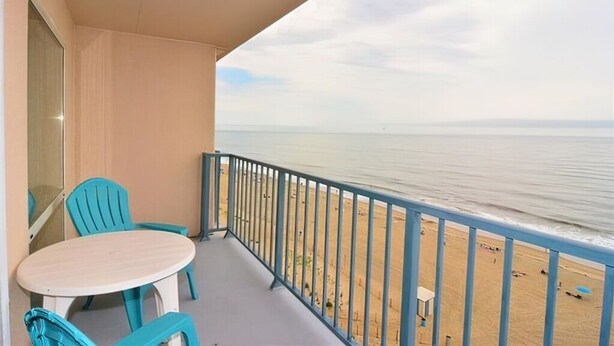 A balcony with a table and chairs, overlooking a beach. - OCEAN FRONT CONDO.  ENJOY YOUR MORNING COFFEE SITTING ON YOUR PRIVATE BALCONY WATCHING THE SUNRISE. (Rehoboth Beach)