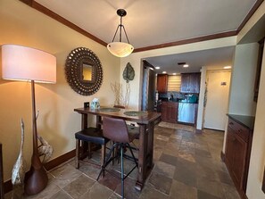 A dining area with a table, chairs, a lamp, and a decorative mirror.