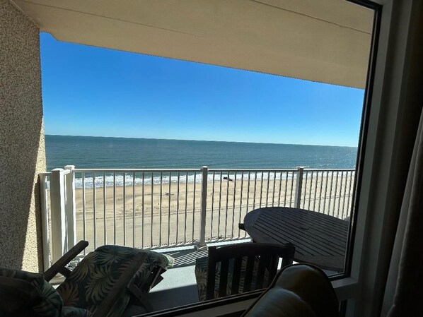 A balcony with a view of the beach and ocean.