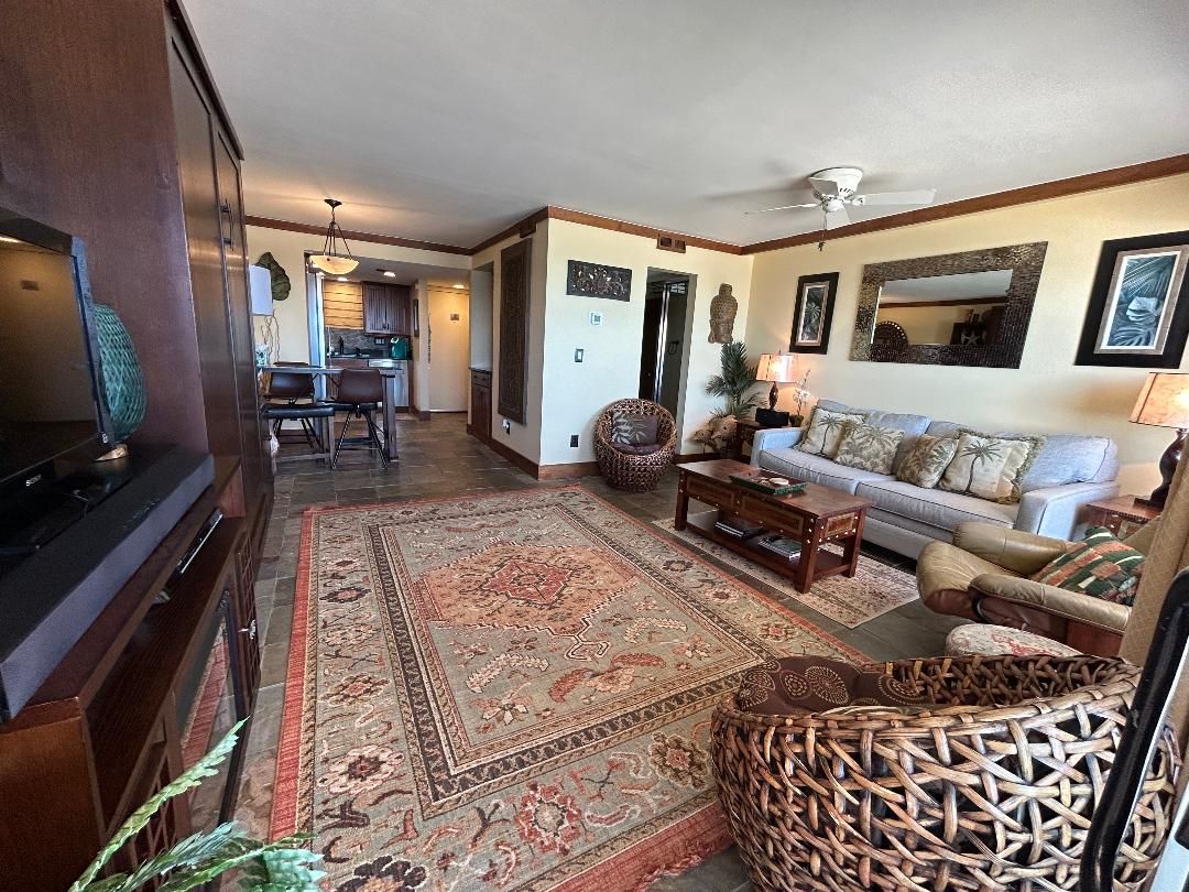 A living room with a sofa, coffee table, and a TV. There is a dining area with chairs and a table.