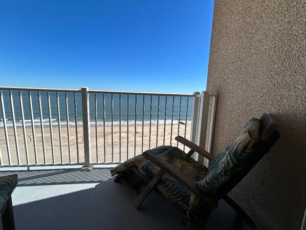 En balkong med utsikt över stranden, en stol och en vägg med en intressant yta.