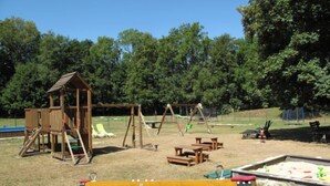 A playground with a wooden playhouse, swings, slides, and picnic tables. - Green Valley Park Stárkov by Interhome (Stárkov)