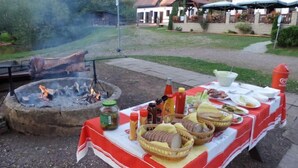 An outdoor dining area with a fire pit, a table set with food and condiments, and a building in the background. - Green Valley Park Stárkov by Interhome (Stárkov)