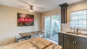A kitchen with a dining area, a ceiling fan, a neon sign, and a sliding glass door leading to a patio. - ★LUXURY RETREAT★ Walk to Hyde Park, SOHO, Bayshore (Tampa)