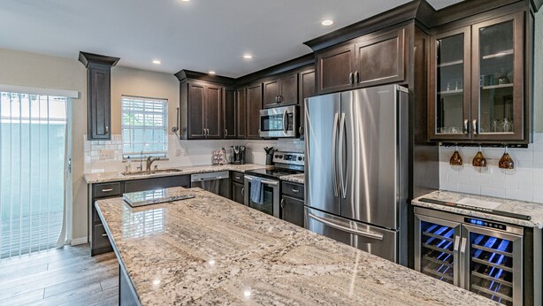 A modern kitchen with dark wood cabinets, stainless steel appliances, and a granite countertop. - ★LUXURY RETREAT★ Walk to Hyde Park, SOHO, Bayshore (Tampa)