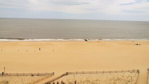 A wide sandy beach with a calm sea and a clear sky.