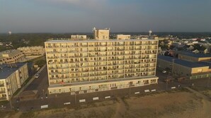 Een hotel met meerdere verdiepingen, een gelijkmatig gevelontwerp, balkons en een parkeerplaats ervoor.