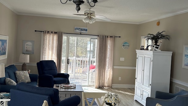 A living room with a ceiling fan, a dining table with placemats, and a white cabinet. - Close enough to the beach but far enough from all of the noise! No pet fee! (Myrtle Beach,)