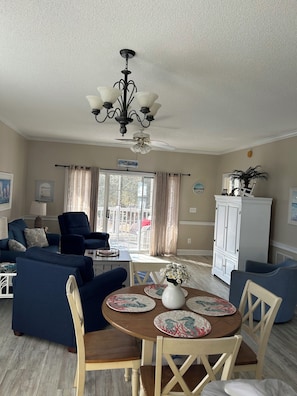 A living room with a ceiling fan, a dining table with placemats, and a white cabinet.