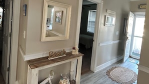 A hallway with a console table displaying a mirror, a small vase, and a decorative item. - Close enough to the beach but far enough from all of the noise! No pet fee! (Myrtle Beach,)