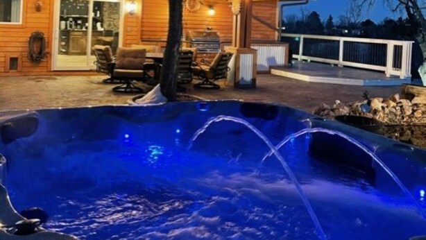 A wooden cabin with a hot tub and outdoor seating. - No Cleaning Fee! Luxury Broadmoor Home w/ Hot Tub & Fire Pit (Broadmoor)
