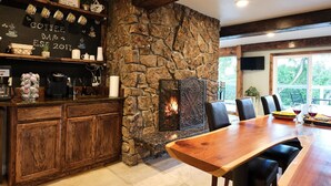 A rustic interior with a stone fireplace, wooden bar, and a dining area with chairs and a table. - No Cleaning Fee! Luxury Broadmoor Home w/ Hot Tub & Fire Pit (Broadmoor)