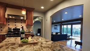 A modern kitchen with granite countertops, a built-in oven, and a wine bottle. - No Cleaning Fee! Luxury Broadmoor Home w/ Hot Tub & Fire Pit (Broadmoor)