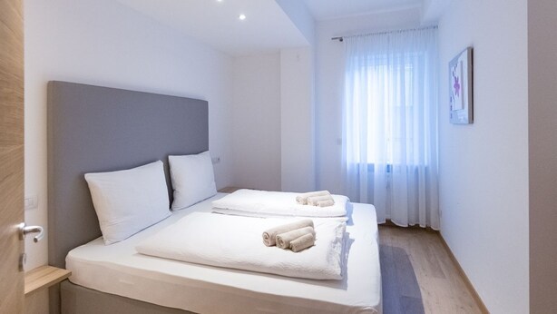 Ein modernes Hotelzimmer mit einem großen Bett, zwei Kissen und ordentlich gefalteten Handtüchern.