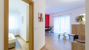 Ein modernes Wohnzimmer mit einer Couch, einem Couchtisch und einem Essbereich mit einem Glastisch und Stühlen.