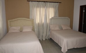 A room with two single beds, a curtain, and a wooden door. - Villa en Guavaberry (Guayacanes)
