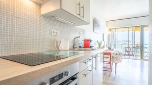 Una cocina moderna con horno empotrado, cafetera y un tostador rojo. Se aprecia una ventana con vistas a la ciudad.
