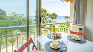 Un balcón con una mesa para dos, con vistas a un paisaje marino y vegetación.