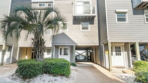 A multi-story residential building with a covered entrance, a palm tree, and a small garden area. - Direct Beachfront, gorgeous sunsets, gated community, north Cape near state park (Port St. Joe)