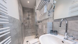 A modern bathroom with a glass-enclosed shower, a white sink, and a towel rack. - Double room - Logierhaus am Rathaus (Norderney)