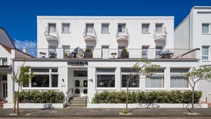 A white building with multiple balconies and a sign reading "Hotel". - Double room - Logierhaus am Rathaus (Norderney)