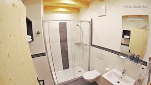 A modern bathroom with a glass shower enclosure, a toilet, and a sink.
