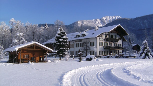 A snow-covered landscape with a wooden cabin and a large building with a balcony.
