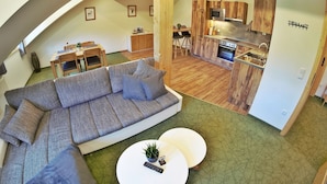 A modern loft-style living space with a large sectional sofa, a dining area, and a kitchen with wooden cabinetry.