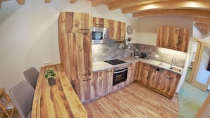 A kitchen with wooden cabinets, a microwave, an oven, and a sink.