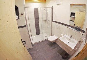 Un baño moderno con cabina de ducha de vidrio, inodoro y lavamanos.