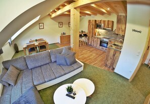 Un espacio habitable moderno estilo loft con un amplio sofá modular, un comedor y una cocina con armarios de madera.