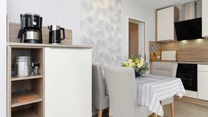 Eine moderne Küche mit Essbereich, ausgestattet mit einer Kaffeemaschine, einer Mikrowelle und Holzschränken.