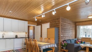 Une cuisine moderne avec des meubles blancs, une table à manger avec des chaises et un coin salon confortable avec un canapé et une table basse.