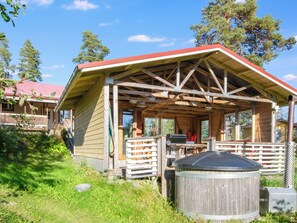 A wooden cabin with a covered porch, a grill, and a water tank. - Villa kaisla by Interhome (Juva)