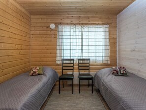A cabin room with two beds, a window with curtains, a radiator, and a rug. - Villa kaisla by Interhome (Juva)