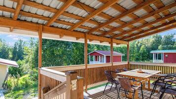 Eine überdachte Holzterrasse mit einem Holztisch und Stühlen, umgeben von einem Holzbalkon.