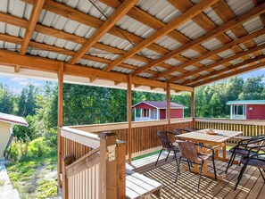 A covered outdoor deck with a wooden table and chairs, surrounded by a wooden railing. - Villa kaisla by Interhome (Juva)