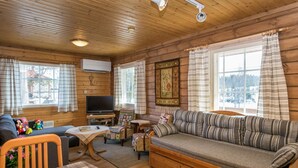 L'intérieur d'un chalet confortable, avec un canapé, un téléviseur et des murs en bois.