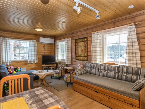 A cozy cabin interior with a sofa, TV, and wooden walls. - Villa kaisla by Interhome (Juva)