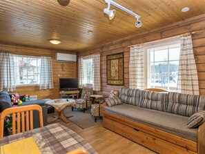 A cozy cabin interior with a sofa, television, and wooden walls. - Villa kaisla by Interhome (Juva)