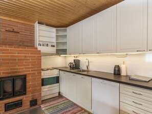 Een keuken met witte kastjes, een fornuis en een koffiezetapparaat.