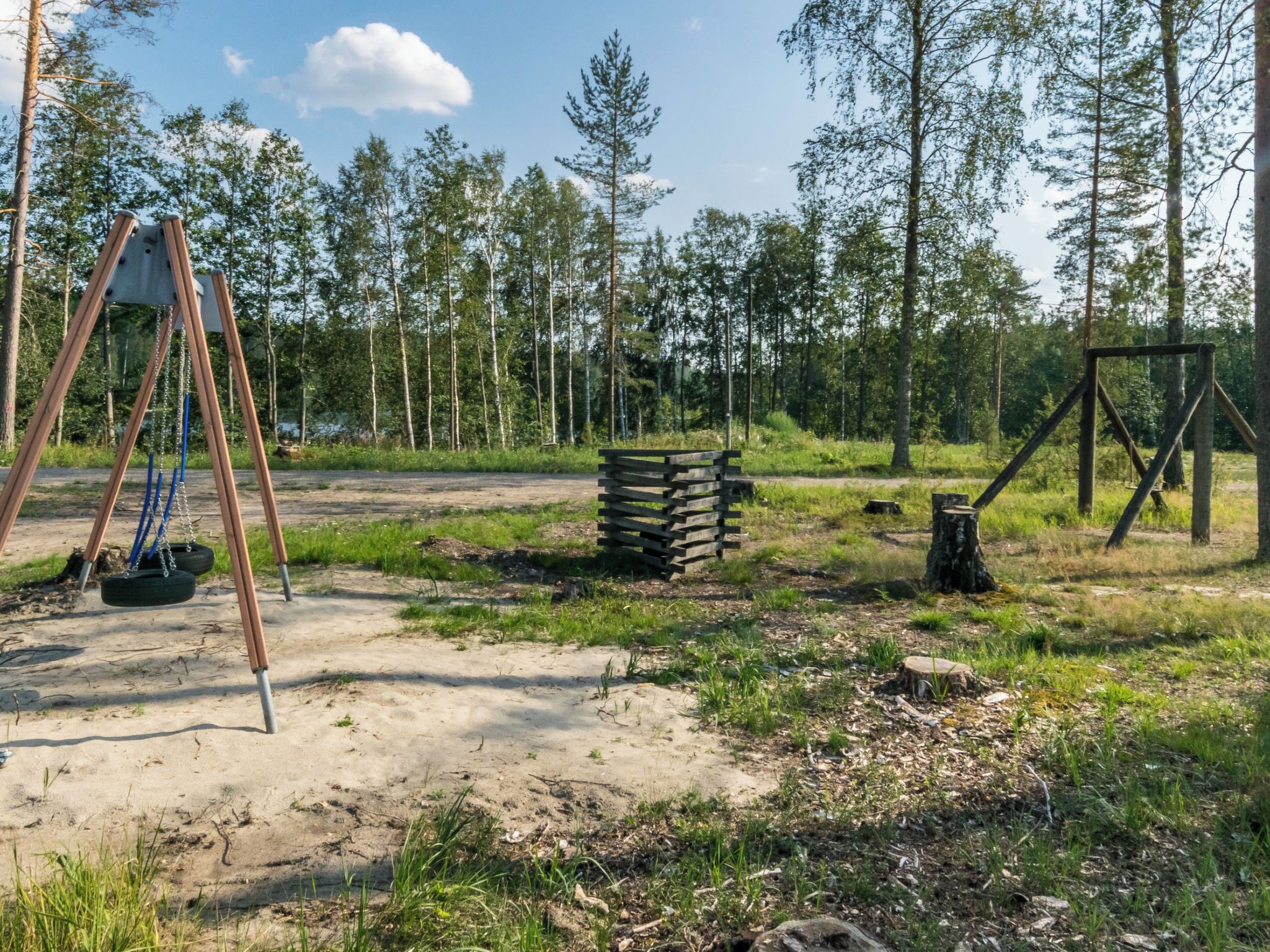 Un'area giochi con altalene e pneumatici appesi, immersa in una zona boschiva.