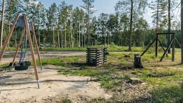 Un'area giochi con altalene e pneumatici appesi, immersa in una zona boschiva.