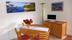 Ein Essbereich mit Tisch, Stühlen, einer Blumenvase, einem Fernseher auf einem Schrank und zwei gerahmten Bildern an der Wand.